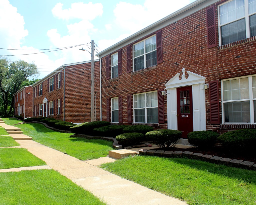 a brick building with a red door and a sidewalk in front of it