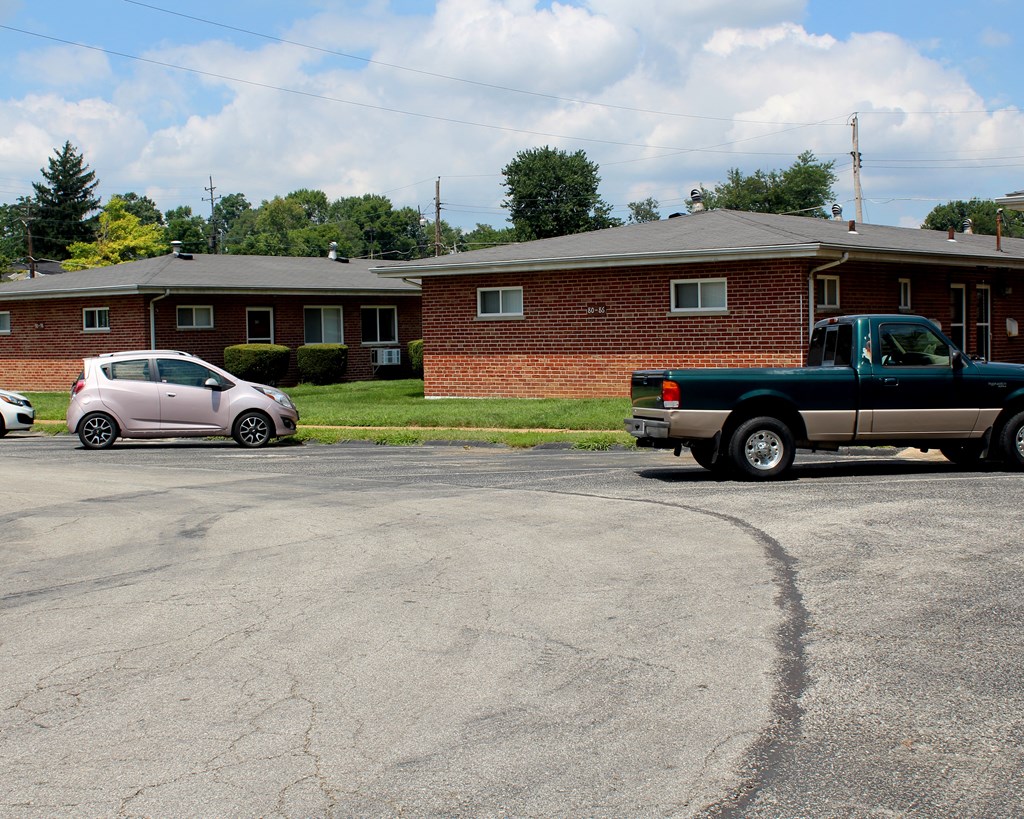 a truck and a car parked in a parking lot in front of a brick house