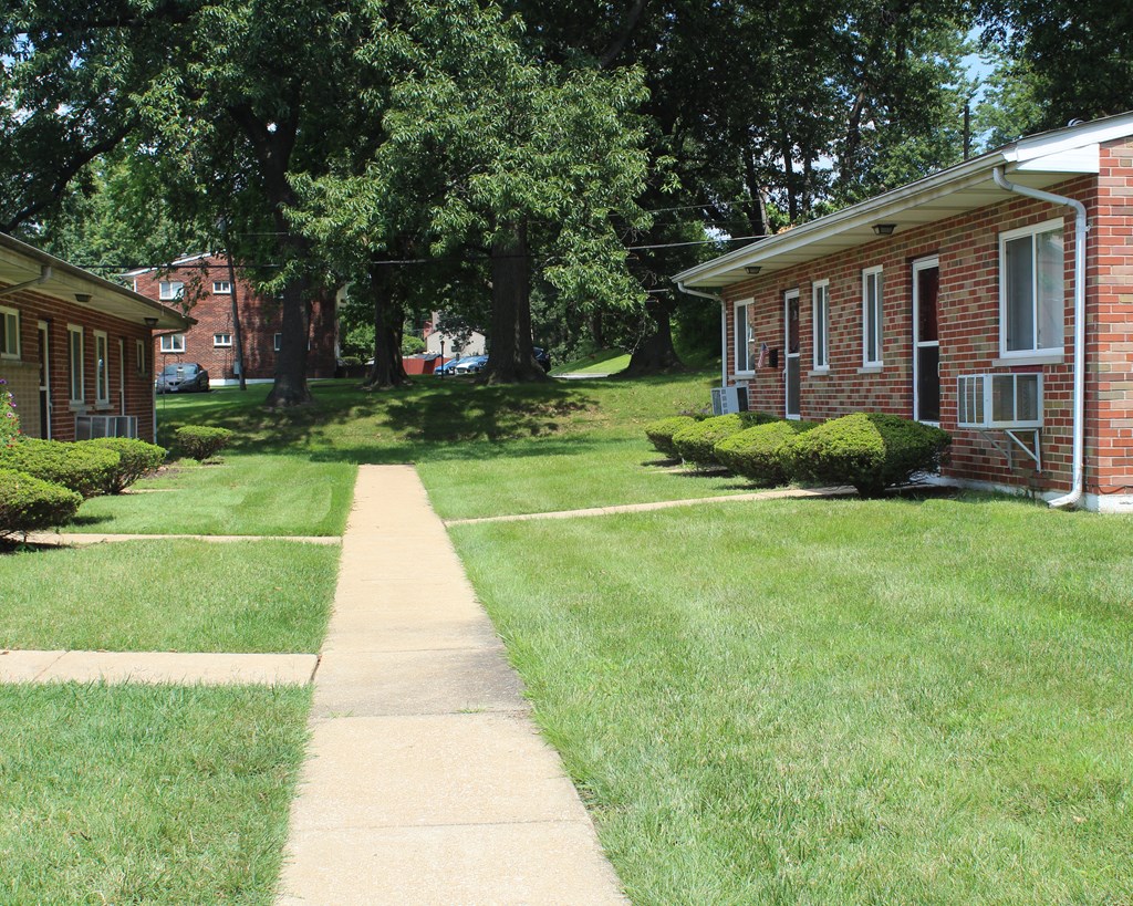 a sidewalk in front of two brick apartment buildings