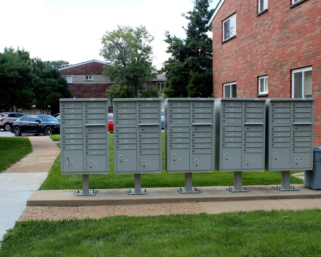 a row of gray metal mailboxes on the side of a sidewalk