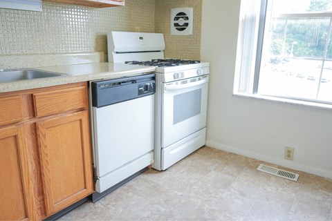 A white stove and dishwasher in a kitchen with wooden cabinets.