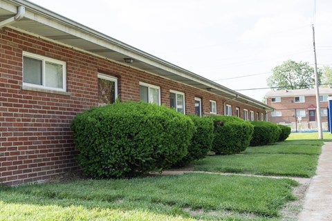 A red brick building with green bushes in front.