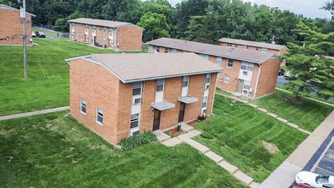 A red brick apartment building with a green lawn in front.