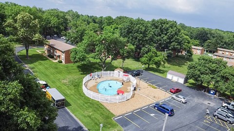 A large swimming pool surrounded by a white fence in the middle of a grassy area.