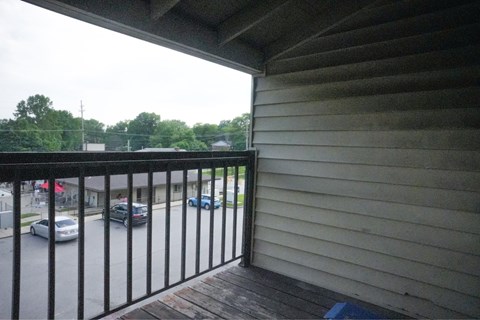 A balcony with a black railing overlooks a parking lot.