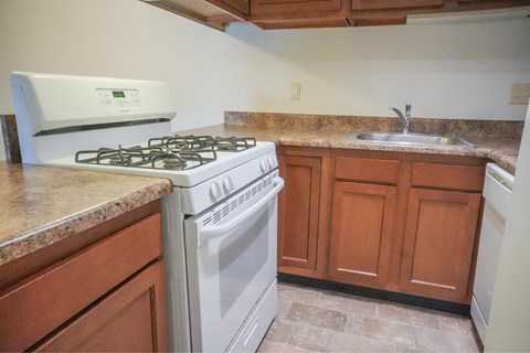A white oven and stove top are in a kitchen with brown cabinets.