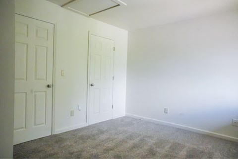 A room with two doors and carpeted floor.