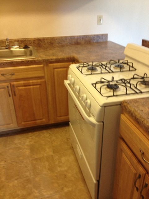 A white gas stove in a kitchen with wooden cabinets.