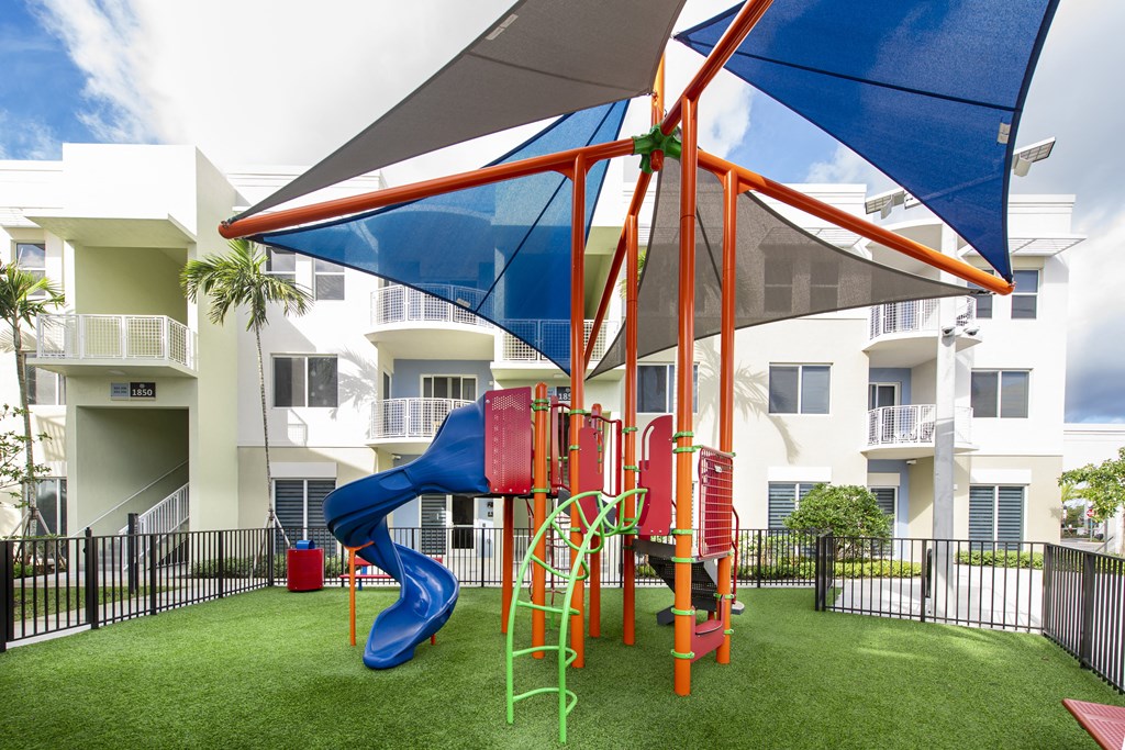 a playground with a blue slide in front of an apartment building