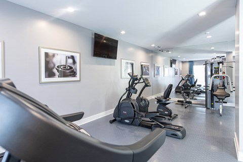 a gym with exercise machines and a tv on the wall