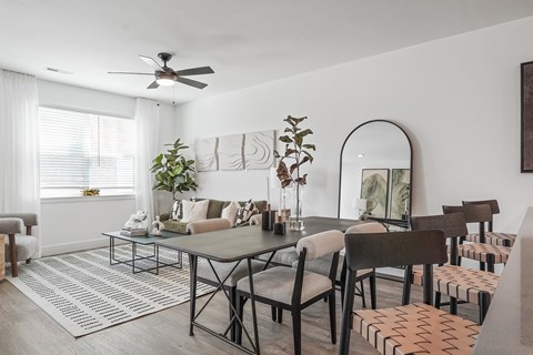 A dining room with a table surrounded by chairs and a mirror on the wall.