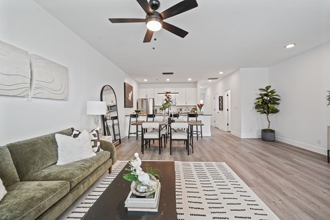 A living room with a green couch and a coffee table with a vase of flowers on it.