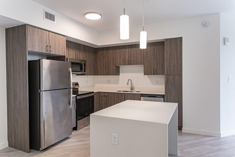 A modern kitchen with a white island and stainless steel appliances.