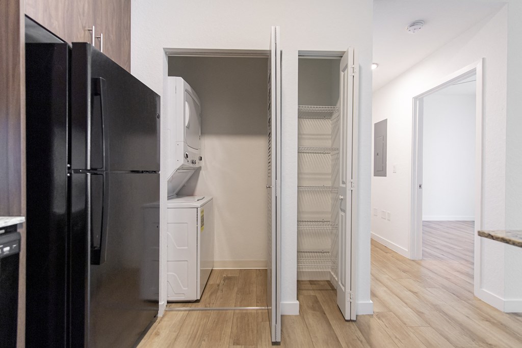 a kitchen with a refrigerator and a closet with a door open