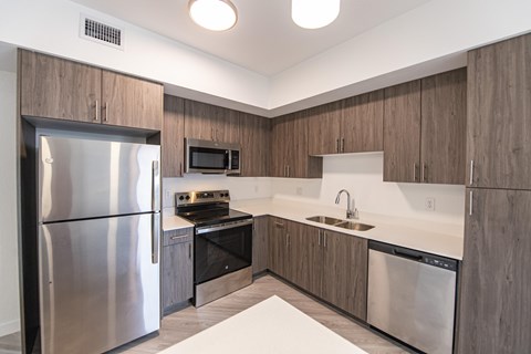 A modern kitchen with a stainless steel refrigerator and a microwave above the stove.