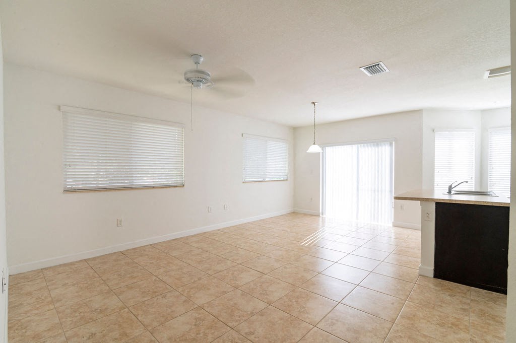 an empty kitchen and living room with tile floors and a ceiling fan