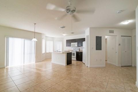A spacious kitchen with a fan and tiled flooring.