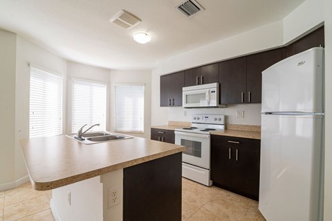 A kitchen with white appliances and brown cabinets.