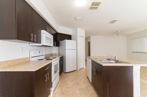 A kitchen with brown cabinets and white appliances.