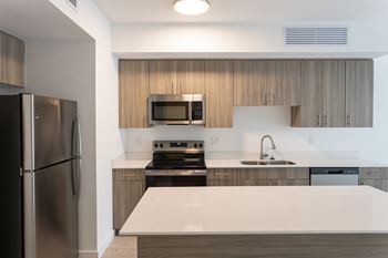A modern kitchen with a stainless steel refrigerator and wooden cabinets.