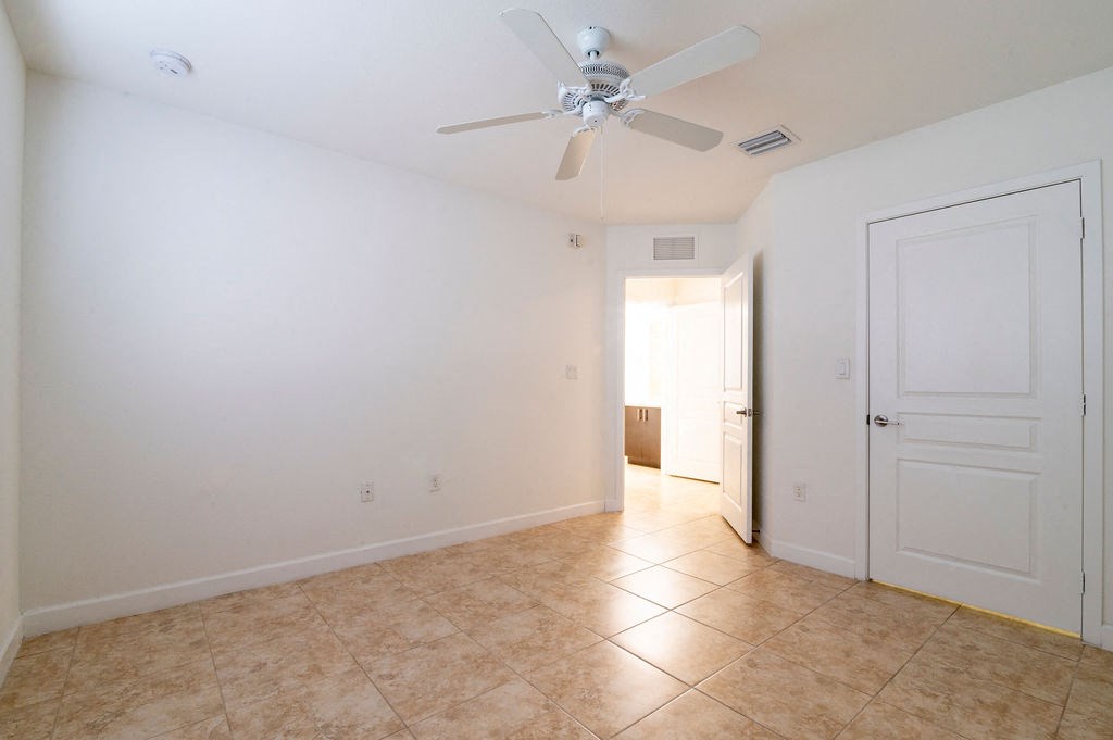 an empty living room with a ceiling fan and a door to a hallway