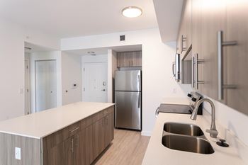 A modern kitchen with a stainless steel refrigerator and a white countertop.
