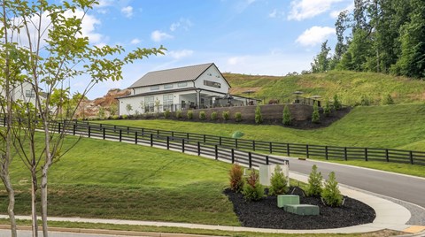 A house with a grey roof is surrounded by a green lawn and a fence.