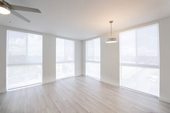 A spacious room with a ceiling fan and large windows.