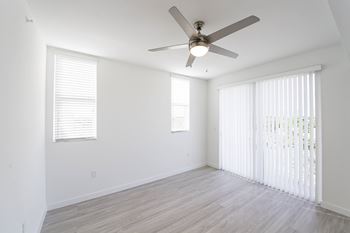 A room with a ceiling fan and a window with blinds.