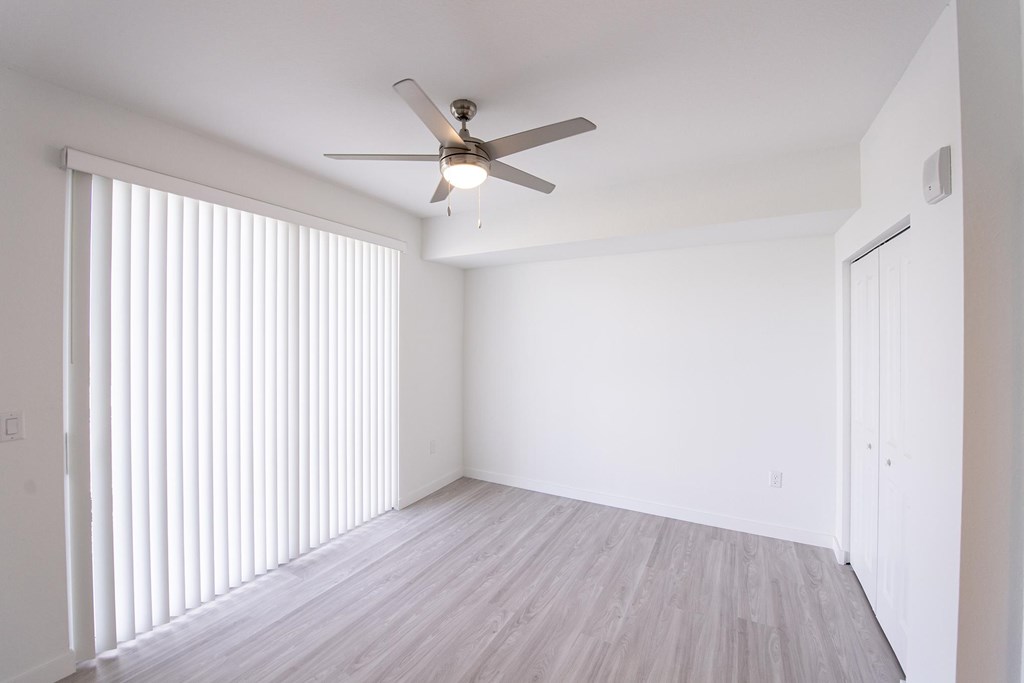 A room with a ceiling fan and sliding glass doors.