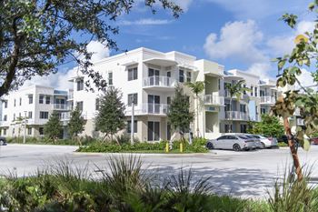 A white apartment building with a car parked in front.