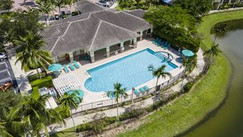 A swimming pool surrounded by palm trees and a building.