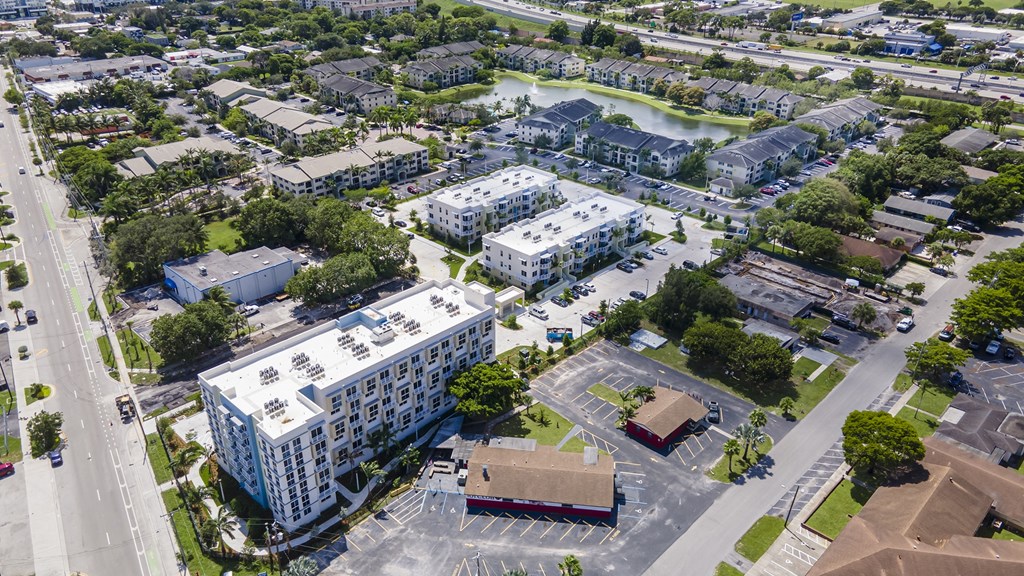 A large white building with a red roof is in the center of a parking lot.