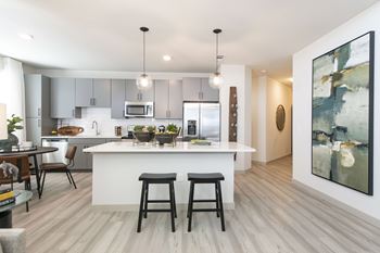A modern kitchen with a white island and bar stools.