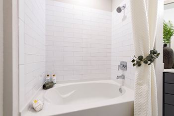 A white bathroom with a white tub and a white shower curtain.