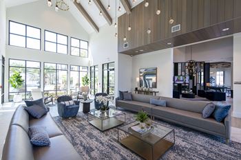 A modern living room with a glass coffee table and a grey sofa.