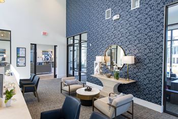 A waiting area with chairs and a table with a lamp.