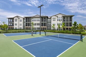 A tennis court in front of a large apartment building.