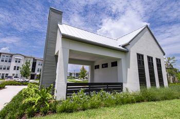 A small white building with a black roof and a black bench in front of it.