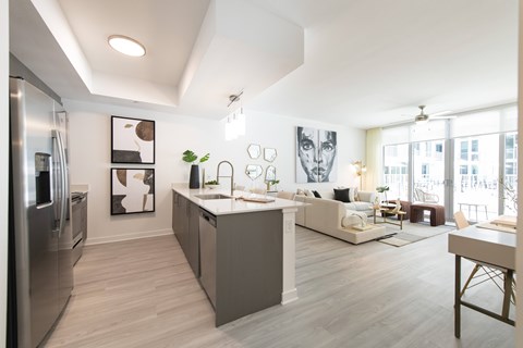 A modern kitchen with a refrigerator, sink, and a dining area with a table and chairs.