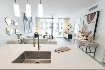 a kitchen counter with a sink and a view of a living room