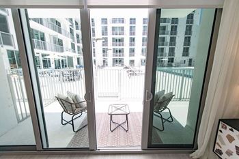 a balcony with chairs and a table in front of a glass door