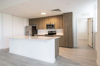 a white kitchen with a large island and a stainless steel refrigerator