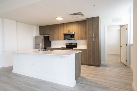 a white kitchen with a large island and a stainless steel refrigerator