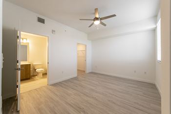 an empty living room with a ceiling fan and a bathroom