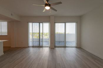 an empty living room with sliding glass doors and a ceiling fan