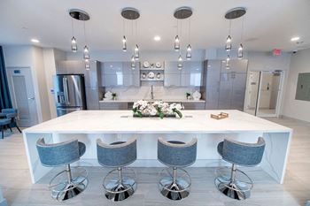 a large kitchen with a white counter top and blue chairs