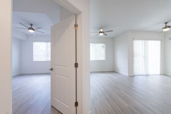 A white door is open in a room with wood flooring and ceiling fan.