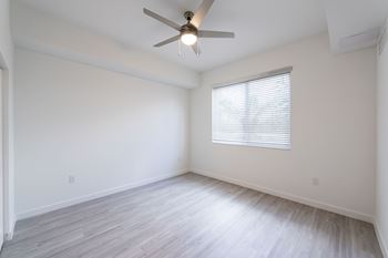 A room with a ceiling fan and a window with blinds.