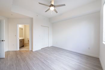 A room with a ceiling fan and light fixture, and a doorway leading to another room.